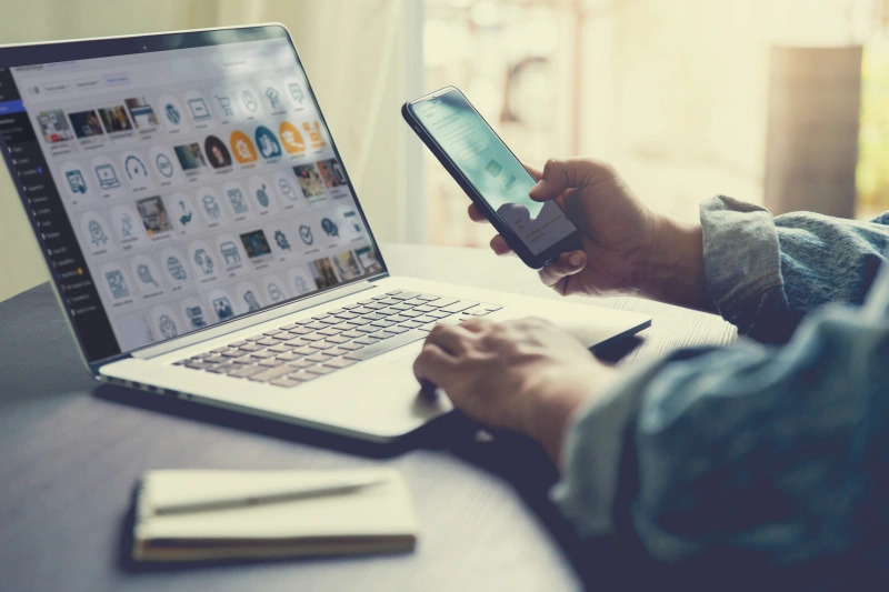 Une personne met à jour un site web sur un ordinateur portable et vérifie les modifications sur son smartphone